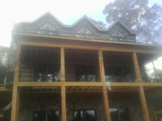 Dormers and porch framing on a large log home under construction — Roof Coating work by our crew in Abington