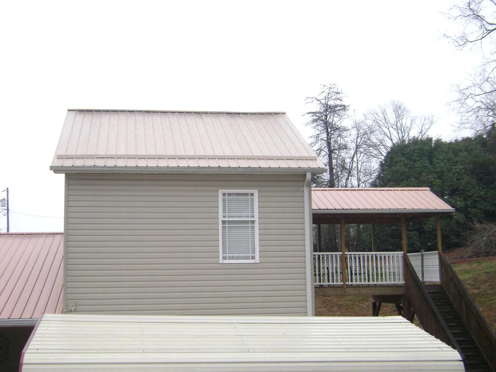 Tan metal roofs on a two story addition and attached porch, from a Roof Replacement job in Abington