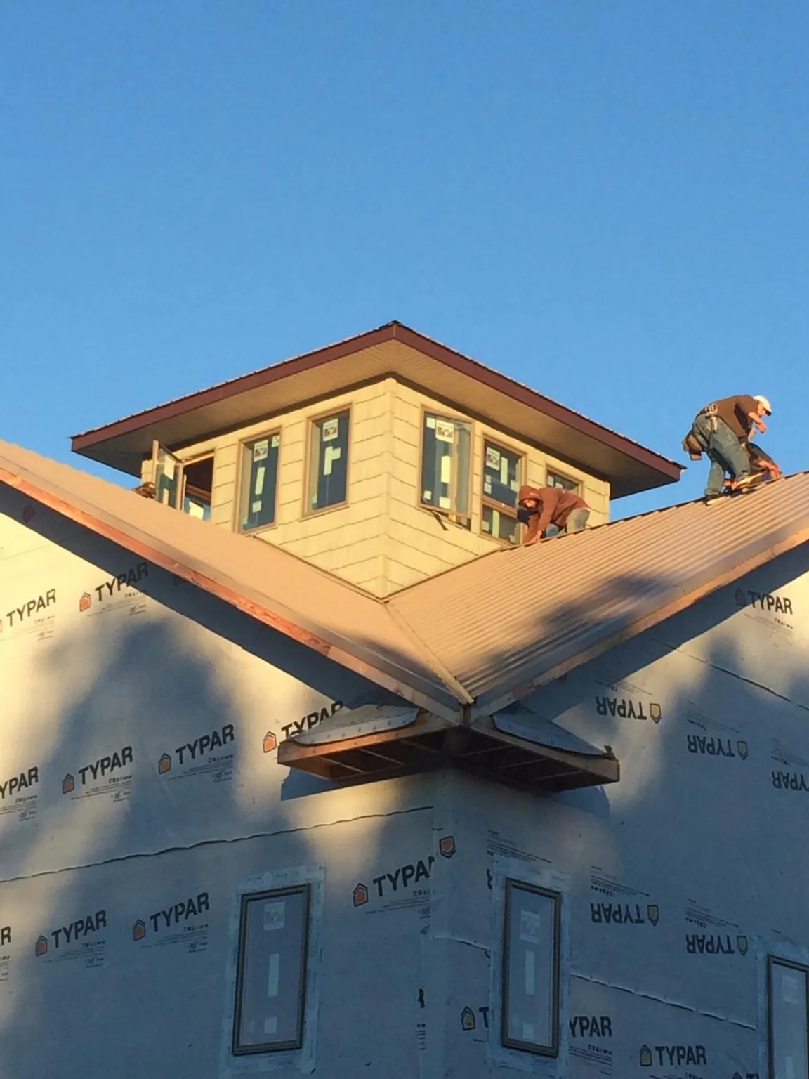 Roofers working around a rooftop cupola on a new metal roof at sunset — Roof Waterproofing in Abington by Roofing Brothers